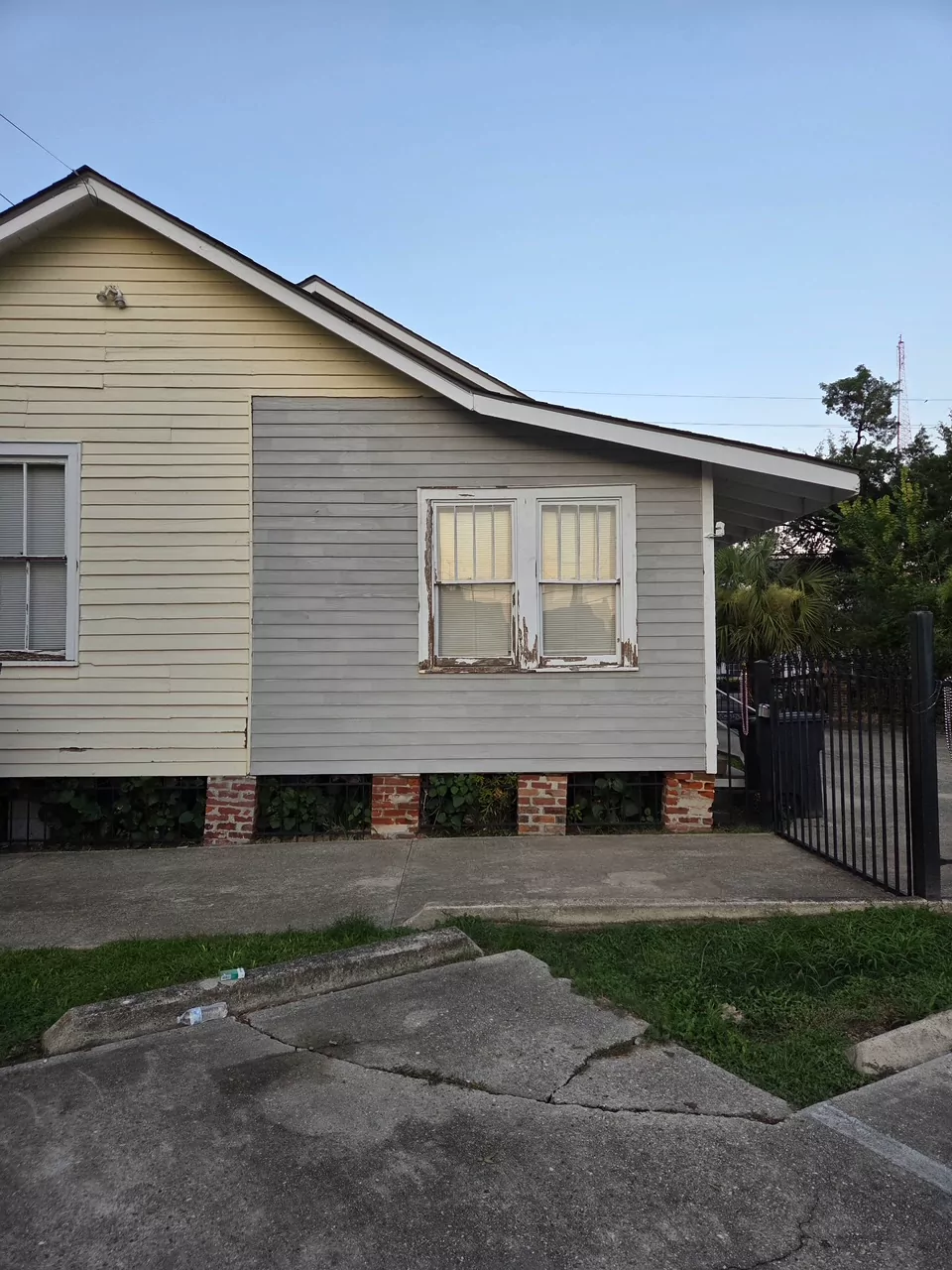 The same house before work started: weathered clapboard siding and an old double window with peeling paint at the gable end.